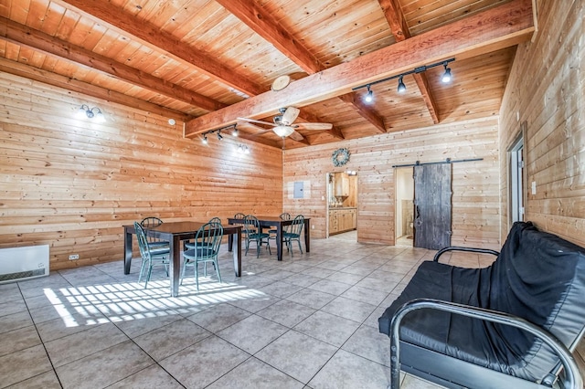 dining area with tile patterned floors, rail lighting, a barn door, and wood walls