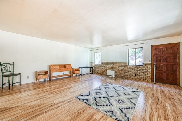 bonus room featuring brick wall and light hardwood / wood-style floors