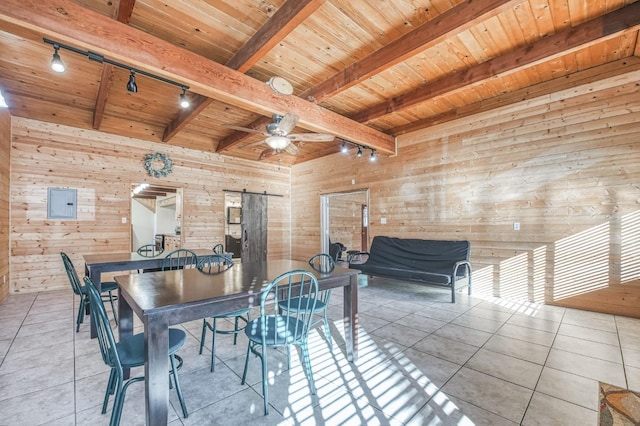 dining area featuring a barn door, wood walls, and track lighting