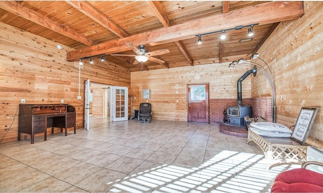 unfurnished living room featuring wood ceiling, tile patterned floors, wooden walls, a wood stove, and rail lighting