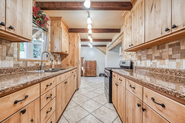 kitchen with light tile patterned floors, stainless steel gas range, light brown cabinetry, beam ceiling, and sink