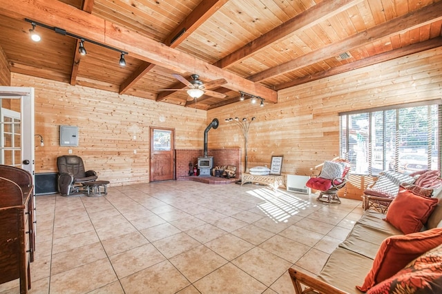 tiled living room with wooden walls, a wood stove, and track lighting