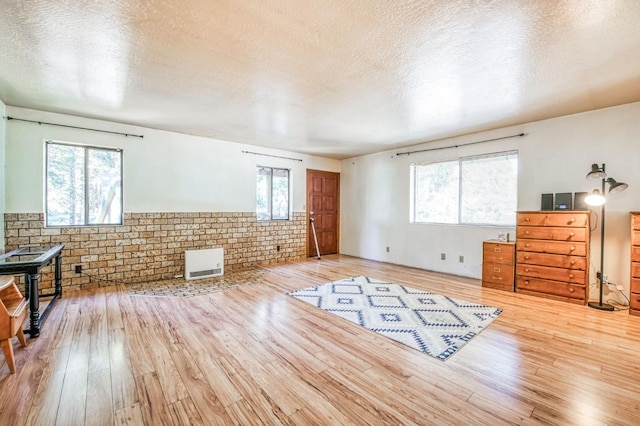 interior space featuring a healthy amount of sunlight, brick wall, a textured ceiling, and hardwood / wood-style flooring