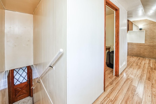 interior space with light hardwood / wood-style floors, wood walls, and lofted ceiling