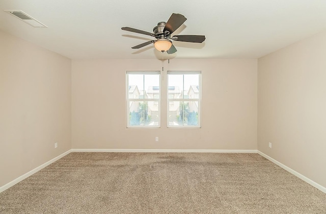 empty room with carpet floors, visible vents, baseboards, and a ceiling fan