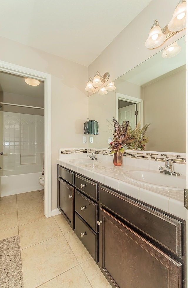 bathroom with tile patterned flooring, a sink, toilet, and double vanity