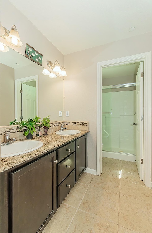 bathroom featuring double vanity, tile patterned flooring, a sink, and a shower stall