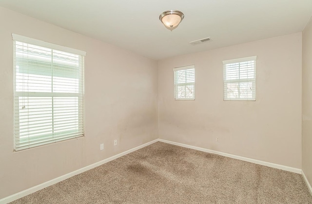 carpeted spare room featuring baseboards and visible vents