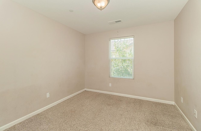 carpeted spare room featuring visible vents and baseboards