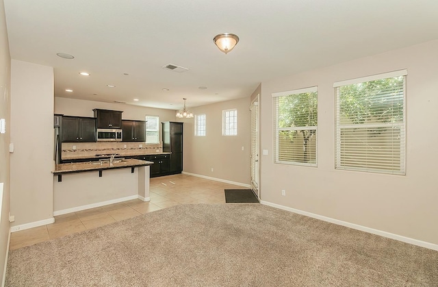 kitchen with a breakfast bar area, light tile patterned floors, stainless steel microwave, decorative backsplash, and light carpet