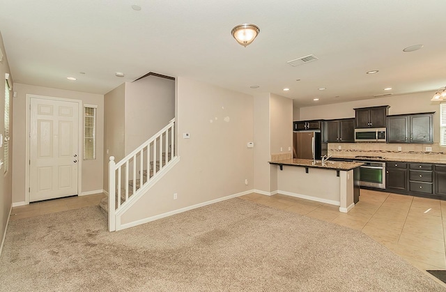 kitchen with light tile patterned floors, a breakfast bar, visible vents, appliances with stainless steel finishes, and backsplash