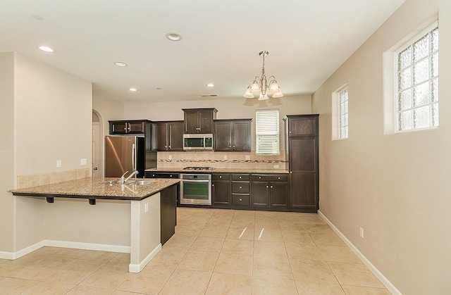 kitchen featuring arched walkways, light tile patterned floors, backsplash, appliances with stainless steel finishes, and baseboards