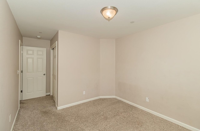 unfurnished room with baseboards and light colored carpet