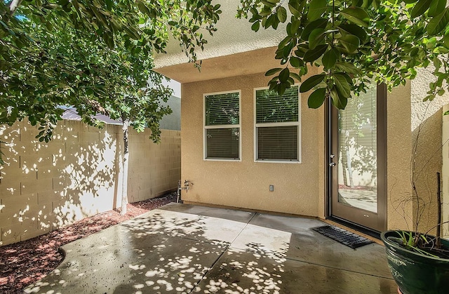 entrance to property featuring visible vents, a patio, fence, and stucco siding