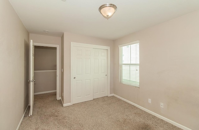 unfurnished bedroom with baseboards, a closet, and light colored carpet