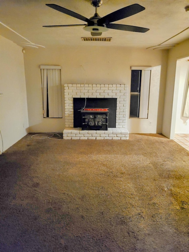 unfurnished living room featuring ceiling fan, a brick fireplace, and carpet