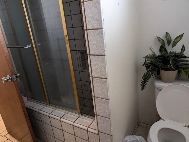 bathroom featuring toilet, tile patterned flooring, and a shower with shower door