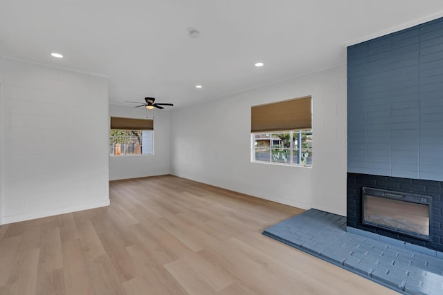 unfurnished living room featuring ceiling fan, a large fireplace, and light hardwood / wood-style flooring