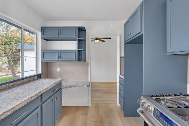 kitchen with light hardwood / wood-style floors, backsplash, ceiling fan, and stainless steel gas range oven