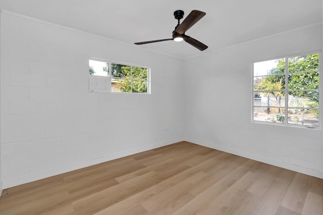 unfurnished room with light wood-type flooring, ceiling fan, ornamental molding, and brick wall