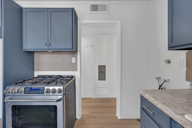 kitchen featuring light hardwood / wood-style floors, light stone counters, blue cabinets, and stainless steel gas range oven