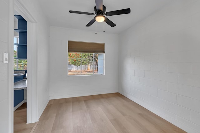 unfurnished room featuring ceiling fan, brick wall, a healthy amount of sunlight, and light hardwood / wood-style floors