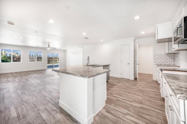 kitchen with white cabinets, sink, light stone counters, and stainless steel appliances