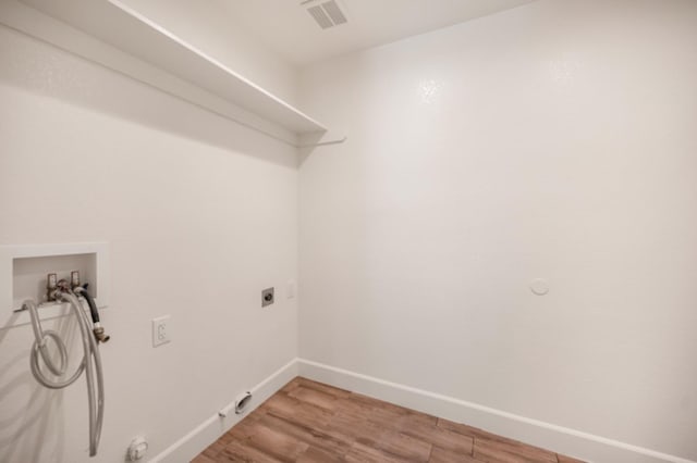 clothes washing area with hookup for an electric dryer, hookup for a washing machine, gas dryer hookup, and hardwood / wood-style flooring