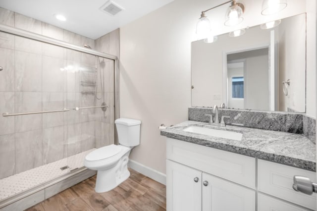 bathroom featuring toilet, a shower with shower door, and vanity