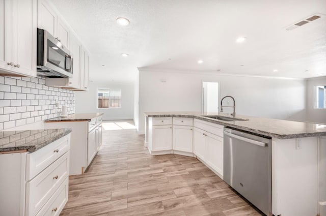 kitchen featuring sink, white cabinetry, a center island with sink, and stainless steel appliances