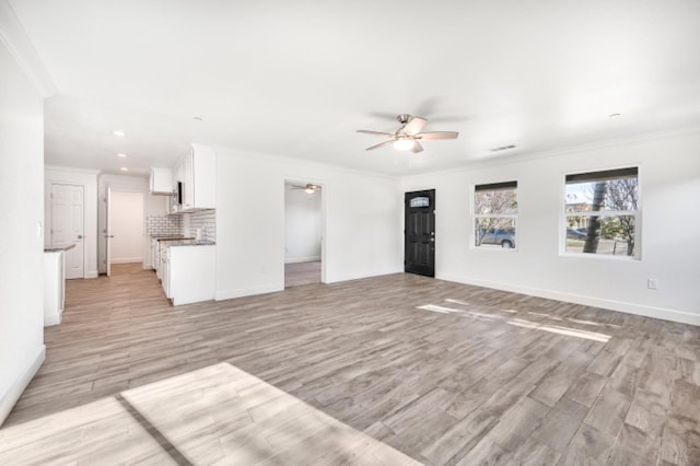 unfurnished living room with ceiling fan, ornamental molding, and light hardwood / wood-style floors