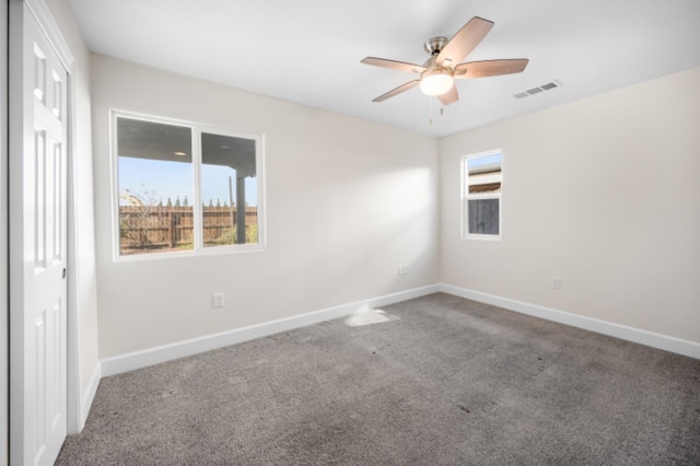 empty room featuring carpet floors, a healthy amount of sunlight, and ceiling fan