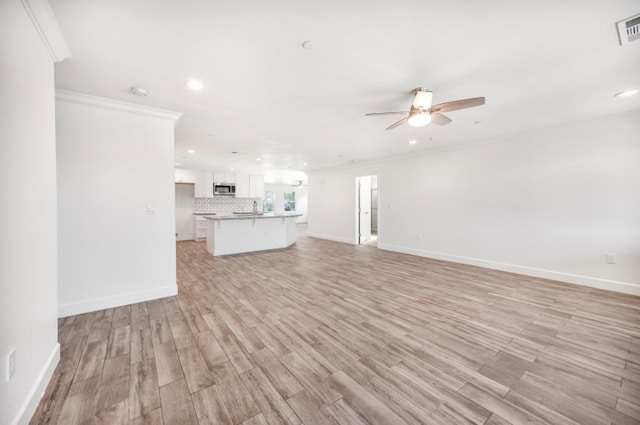 unfurnished living room with ceiling fan, ornamental molding, and light wood-type flooring