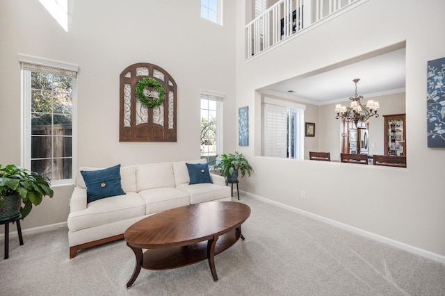 living room with carpet floors, an inviting chandelier, a high ceiling, and ornamental molding