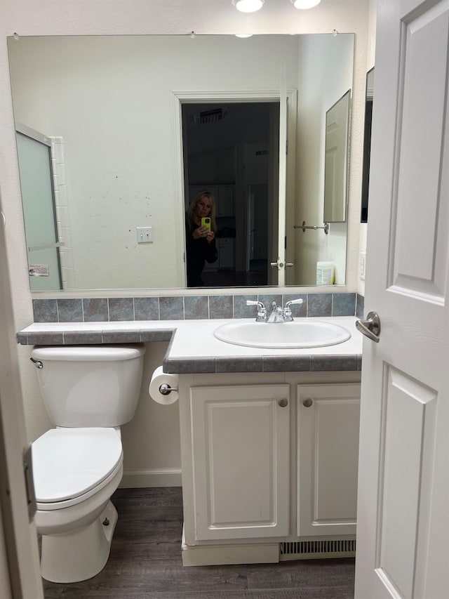 half bath with toilet, vanity, and wood finished floors