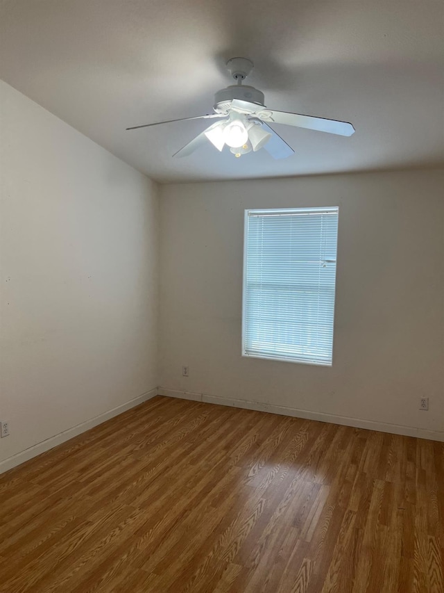 empty room with ceiling fan, wood finished floors, and baseboards