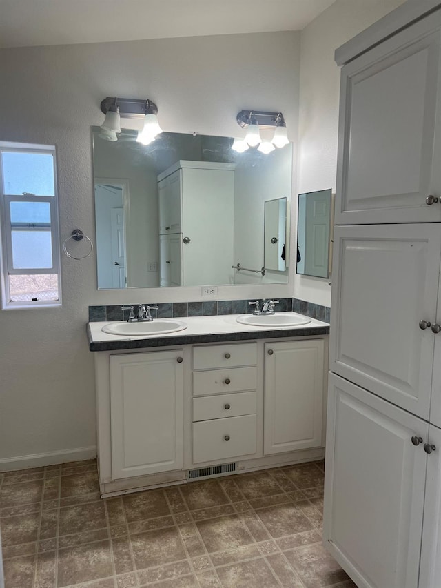 bathroom with double vanity, a sink, and visible vents