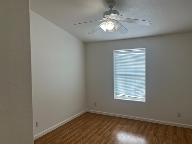 spare room with baseboards, a healthy amount of sunlight, wood finished floors, and a ceiling fan