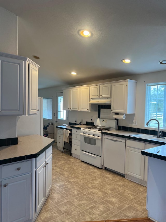 kitchen featuring white appliances, under cabinet range hood, a sink, and recessed lighting