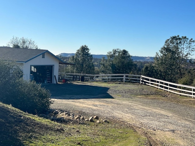 view of yard with an outbuilding, driveway, and fence