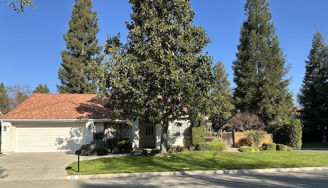 view of property hidden behind natural elements featuring a front yard and a garage