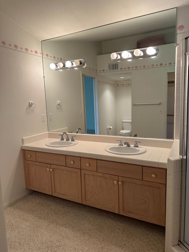 bathroom with toilet, an enclosed shower, and vanity