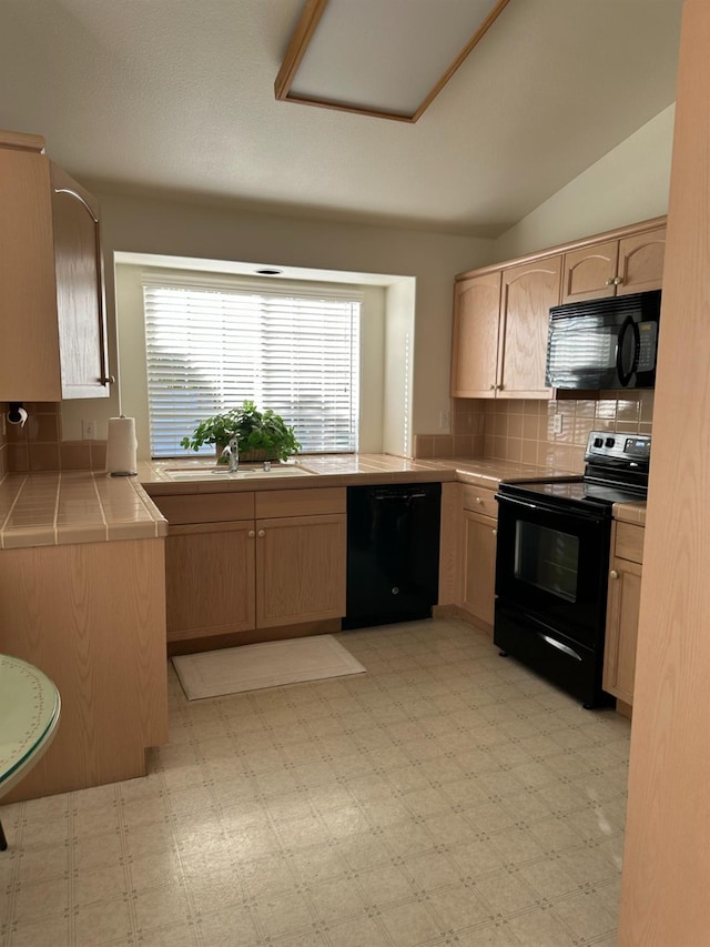 kitchen featuring tile countertops, decorative backsplash, light brown cabinetry, black appliances, and sink