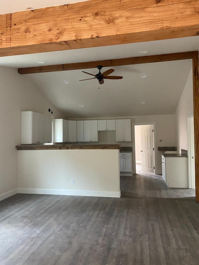 unfurnished living room with ceiling fan, dark wood-type flooring, and vaulted ceiling with beams