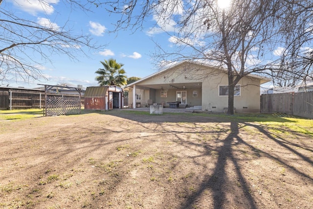 rear view of property with a storage shed, a lawn, and a patio