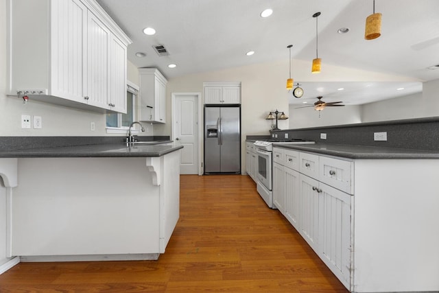 kitchen featuring white cabinetry, stainless steel fridge, white range with gas cooktop, lofted ceiling, and pendant lighting