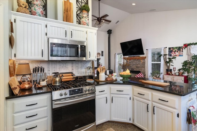 kitchen with tasteful backsplash, lofted ceiling, kitchen peninsula, appliances with stainless steel finishes, and white cabinets