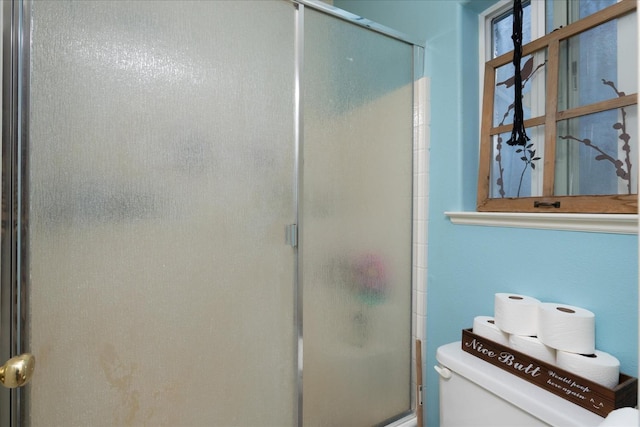 bathroom with toilet and a shower with door