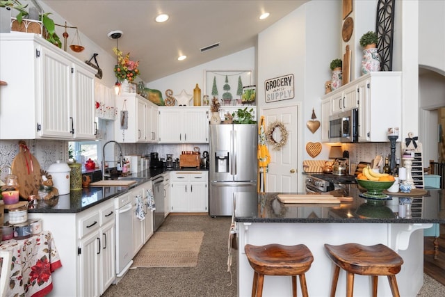 kitchen featuring white cabinetry, lofted ceiling, stainless steel appliances, and tasteful backsplash