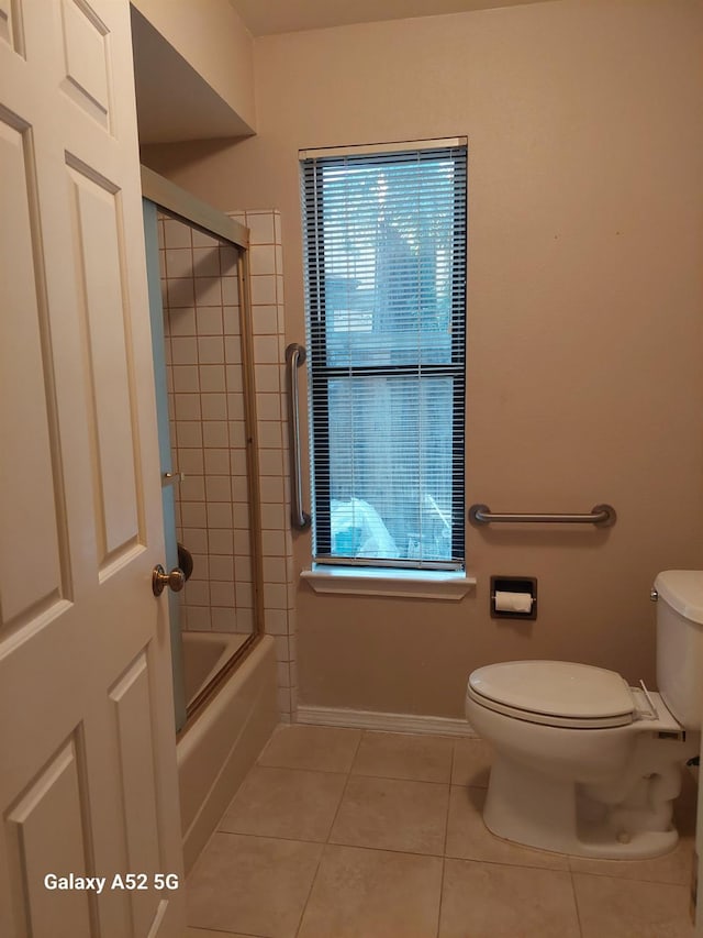 bathroom featuring toilet, tile patterned floors, and enclosed tub / shower combo